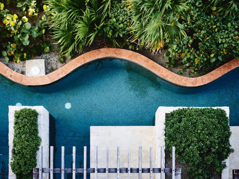 A family-friendly backyard pool with a mix of rectangular and curved shapes surrounded by landscaping and a patio.