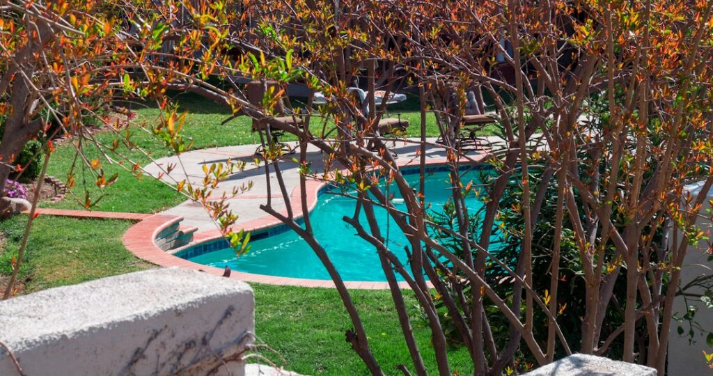 Homeowner secures a winter pool cover while leaves collect on the surrounding backyard deck.